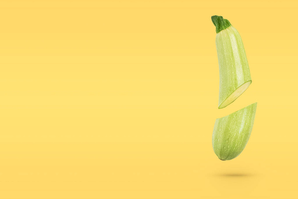 Fresh organic vegetable marrow, cut in half, floats freely in the air against a yellow background. The concept of fresh vegetables, diet, flying food. Copy space for text. - Foto, Imagem