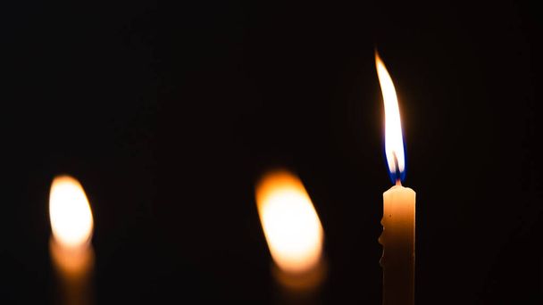 Κοντινές λήψεις από κίτρινα κεριά και φώτα σε μαύρο φόντο με φώτα bokeh - Φωτογραφία, εικόνα
