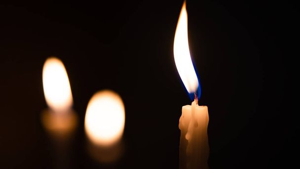 Close-up shots of yellow candles and lights on a black background with bokeh lights - Foto, Imagen