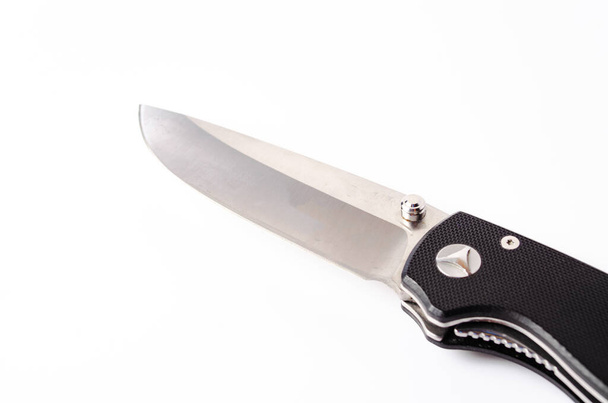 Ένα πτυσσόμενο μαχαίρι με μαύρη λαβή σε λευκό φόντο, ανοιχτό και κλειστό. Κορδόνι με κορδόνι στο μαχαίρι. Τακτικό πτυσσόμενο μαχαίρι σε κοντινό πλάνο - Φωτογραφία, εικόνα