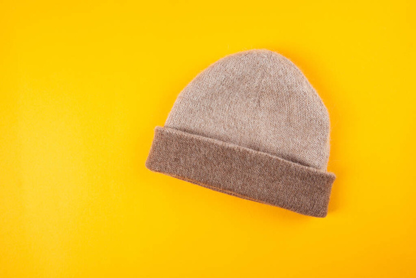Beige lana caliente visón alpaca sombrero de punto sobre fondo amarillo
 - Foto, imagen
