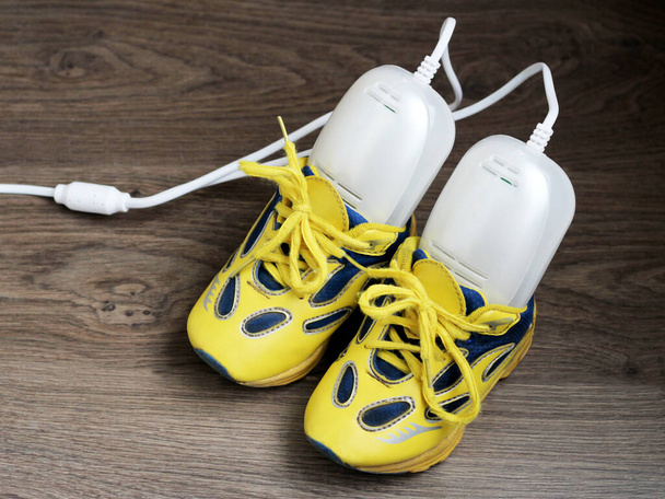 Secador de sapatos ultravioleta elétrico e tênis amarelo tão perto
 - Foto, Imagem