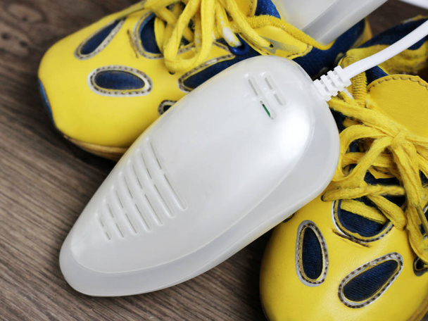 Electric ultraviolet shoe dryer and yellow sneakers so close - Photo, Image