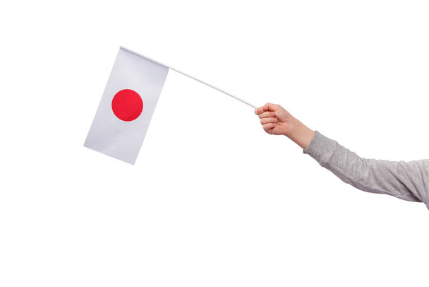 Παιδικό χέρι κρατά σημαία της Ιαπωνίας απομονώνονται σε λευκό φόντο. Λευκή σημαία με κόκκινο κύκλο - Φωτογραφία, εικόνα