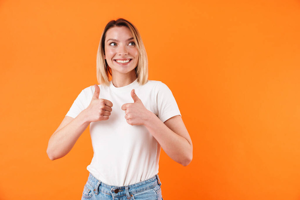 Image of joyful caucasian woman smiling and gesturing thumbs up isolated over orange background - Zdjęcie, obraz