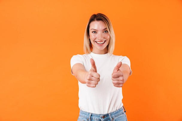 Imagem de mulher caucasiana alegre sorrindo e gesticulando polegares isolados sobre fundo laranja
 - Foto, Imagem