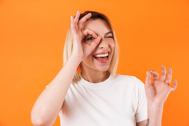 Image of joyful caucasian woman smiling and gesturing ok sign isolated over orange background - Fotoğraf, Görsel