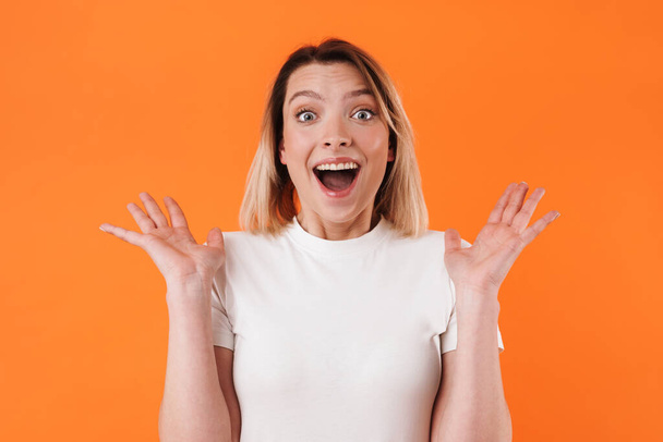 Image of beautiful excited woman expressing surprise on camera isolated over orange background - Photo, Image