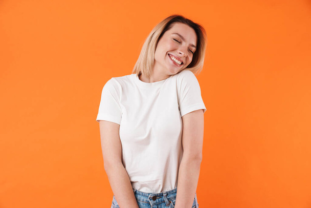 Image of joyful attractive woman laughing with eyes closed isolated over orange background - Fotó, kép