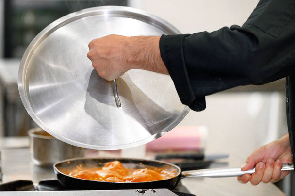 Großaufnahme, Koch deckt Pfanne mit Deckel in Restaurantküche zu - Foto, Bild