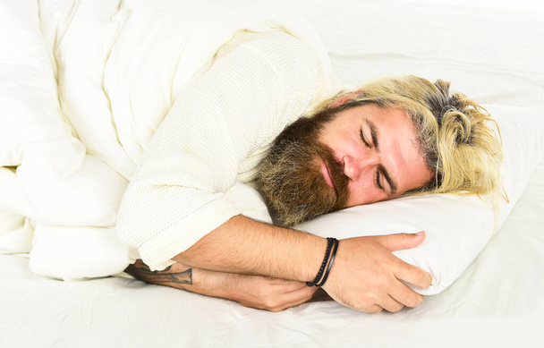 bearded mature man lying on bed at home. Carefree guy enjoying a new day. good morning routine. Caucasian bearded guy wearing white bathrobe. relax in a hotel room in a robe. More coffee - Foto, Imagen