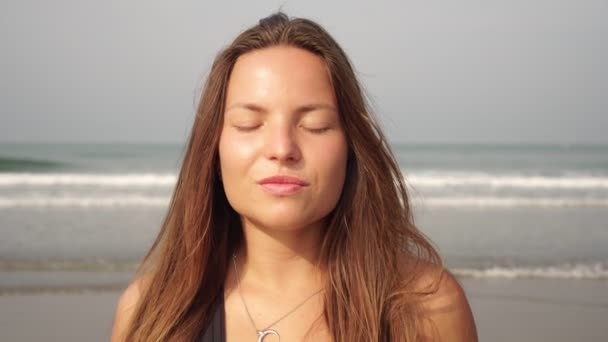 Portret młodej kobiety na tle morza z zamkniętymi oczami - Materiał filmowy, wideo