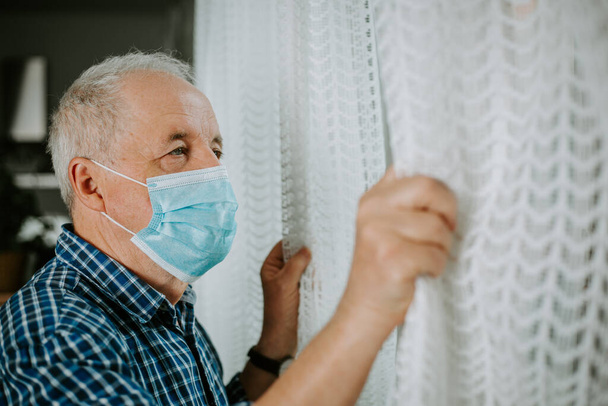 Starszy mężczyzna poddany kwarantannie w domu podczas pandemii koronawirusowej, bądź bezpieczny. - Zdjęcie, obraz
