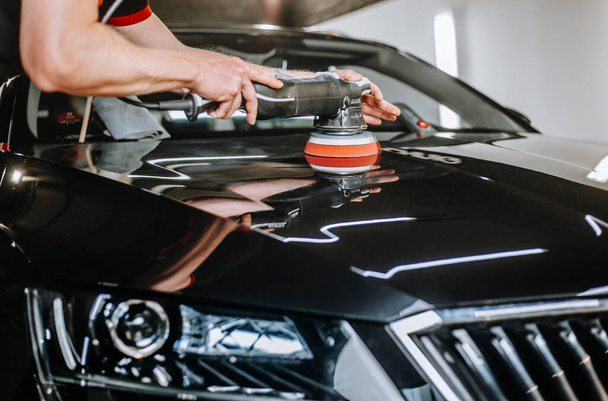 Professional detailing a car in car studio, hands with orbital polisher, scratching remover, vehicle care concept - Fotó, kép
