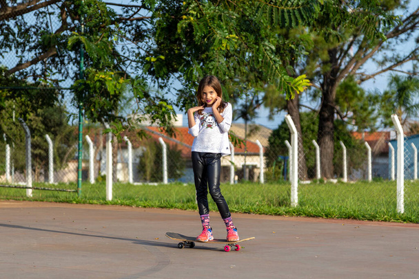 美しいですブロンドの女の子に乗ってスケートボードで公園で日没. - 写真・画像
