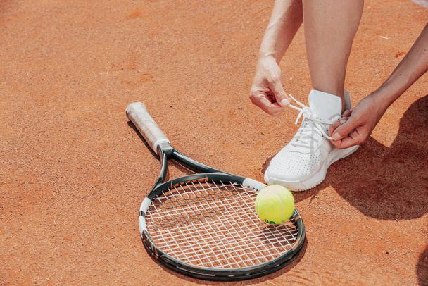 Tennis player on a getting ready tying shoes laces before her professional match, sport concept - Фото, изображение