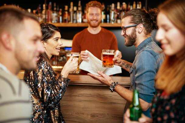 Bir grup arkadaş bira içiyor, sohbet ediyor ve barda eğleniyorlar.. - Fotoğraf, Görsel
