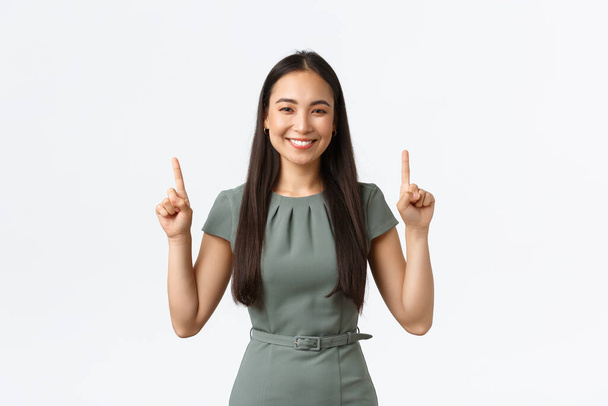 Kleinunternehmer, Unternehmerinnen. Lächelnde selbstbewusste asiatische Geschäftsfrau lädt zum Besuch ihres Online-Shops ein, zeigt mit dem Finger auf Werbebanner, weißer Hintergrund - Foto, Bild