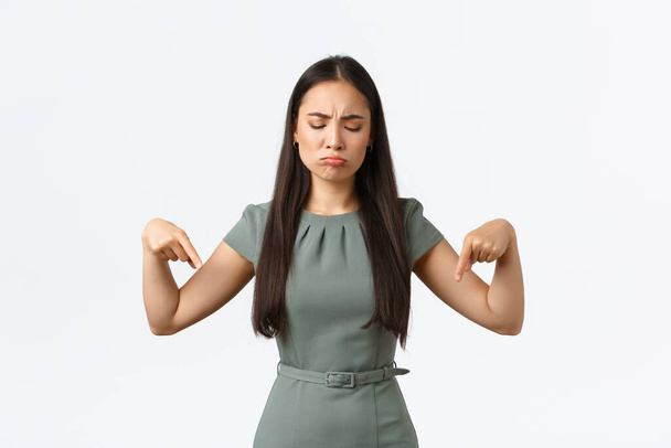 Small business owners, women entrepreneurs concept. Disappointed gloomy asian woman complaining unfair situation, looking with regret and jealousy, pointing fingers down upset - Photo, Image