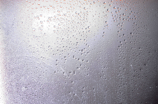 Gocce d'acqua su uno sfondo sfocato in primo piano. Gocce di pioggia su sfondo tramonto. Acqua su vetro. Gocce appendere - Foto, immagini