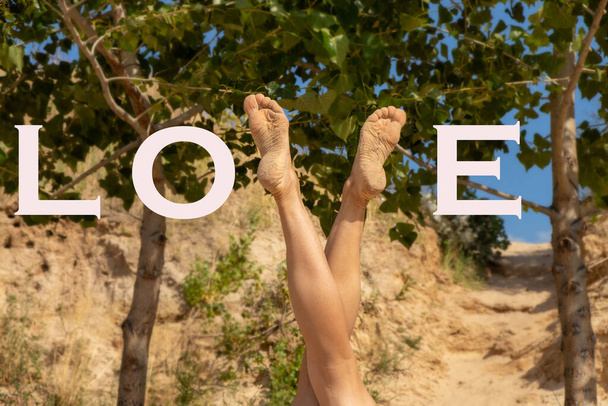 nogi młodej dziewczyny na tle zielonych drzew w kształcie litery V ze słowem miłość w języku angielskim - Zdjęcie, obraz