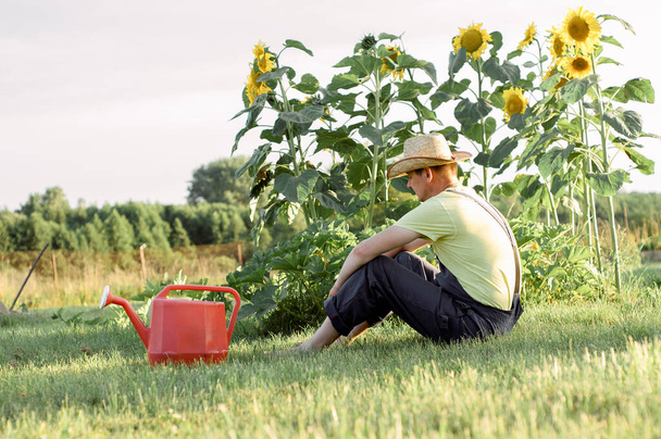 Portret brodatego mężczyzny w słomkowym kapeluszu relaksującego się w ogrodzie  - Zdjęcie, obraz