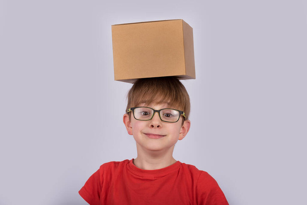 Χαρτονένιο κουτί στο κεφάλι του αγοριού. Παιδικό κουτί στο κεφάλι του. - Φωτογραφία, εικόνα