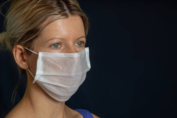 meisje in medisch masker portret op donkere achtergrond - Foto, afbeelding