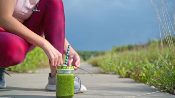 Woman running outdoors with green detox smoothie - Footage, Video