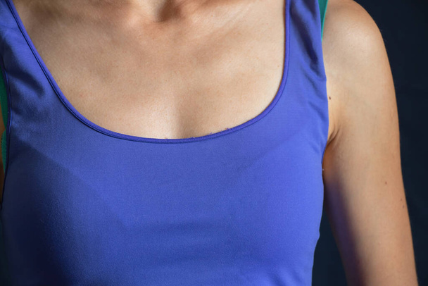 chest of a girl in a blue t-shirt on a dark background - Foto, Imagen