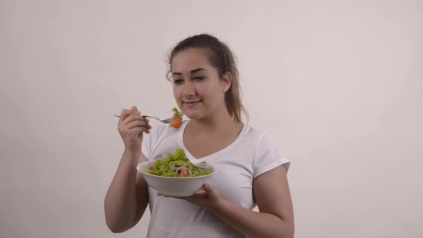 Estilo de vida saludable chica joven en camiseta blanca comiendo una ensalada fresca sonriendo feliz
 - Metraje, vídeo