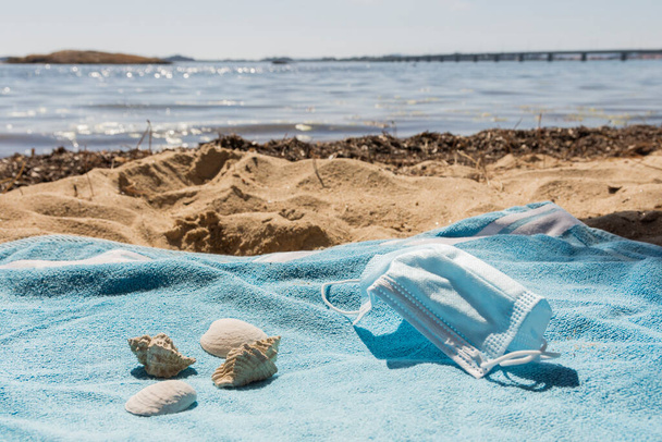 widok na plażę z ręcznika z maską w słoneczny dzień. Towarzyszą mu niektóre muszle. - Zdjęcie, obraz