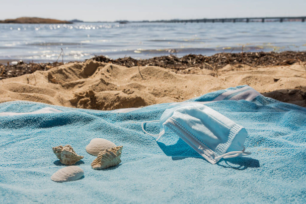 uitzicht op het strand vanaf de handdoek met het masker op een zonnige dag. Vergezeld van enkele schelpen. - Foto, afbeelding