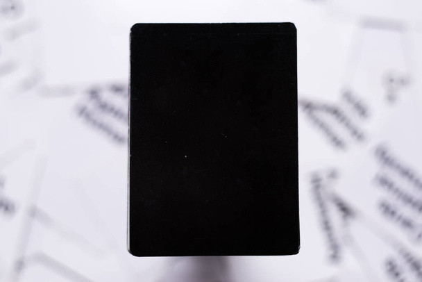 Ylhäältä alaspäin näkyvä tyhjä musta kortti valkoisella taustalla epätarkka. Tunnistamaton ääriviivat sanoja ja kortteja taustalla - Valokuva, kuva