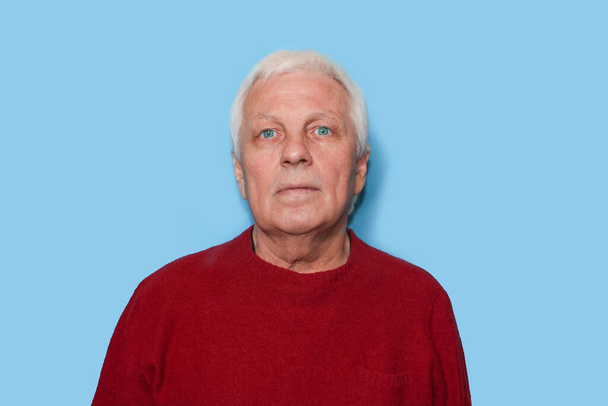 Selbstbewusster Senior in Formalbekleidung blickt vor blauem Hintergrund in die Kamera - Foto, Bild