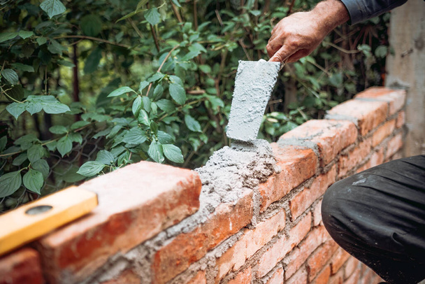 Construction bricklayer worker building with bricks, mortar, trowel. Industry details - Фото, изображение