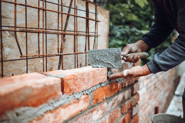 Professional worker using pan knife for building brick walls with cement and morta - Фото, зображення
