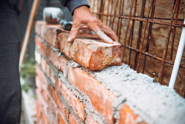 professional construction worker laying bricks and building walls on industrial construction site. Detail of hand adjusting brick - Φωτογραφία, εικόνα