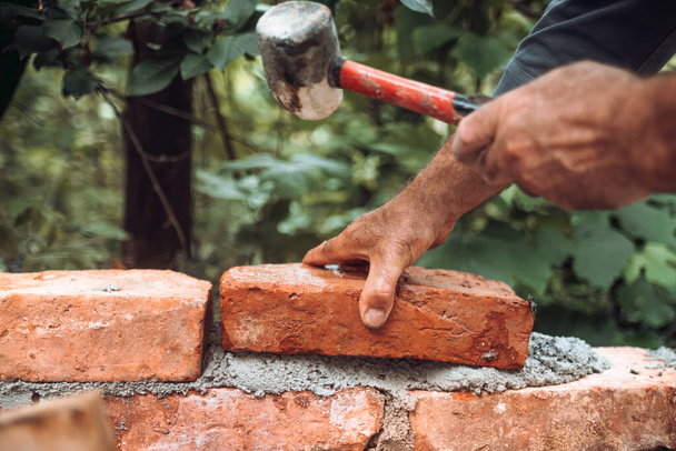 Close up of industrial worker, bricklayer installing bricks on construction site - Фото, изображение