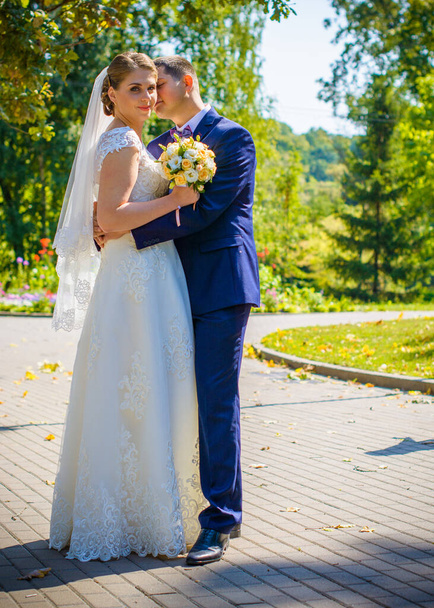 Happy bride and groom after wedding ceremony .Groom is younger than the bride. Wedding couple, newlyweds in a park kissing - Photo, Image