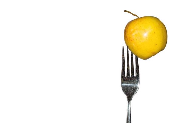 gele appel op een vork met witte achtergrond - Foto, afbeelding