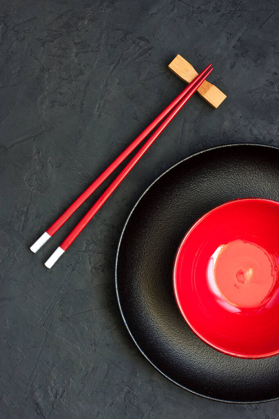 Empty black and red  bowl and wooden chopsticks on concrete background, top view.  Asian food concept - Fotografie, Obrázek