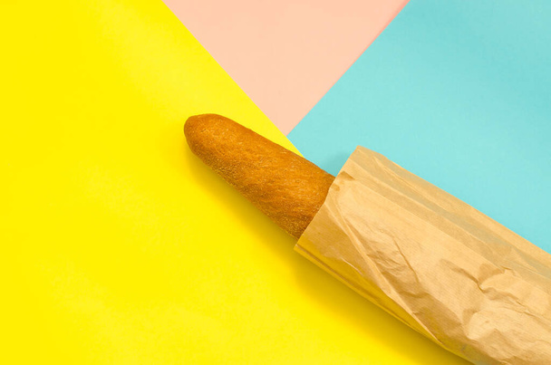 Rye baguette in a paper bag. Bread in a bag on a colorful background. Bakery products - Photo, Image