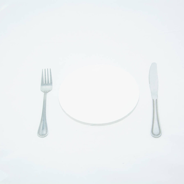 Assiette blanche avec couverts sur fond blanc - Photo, image
