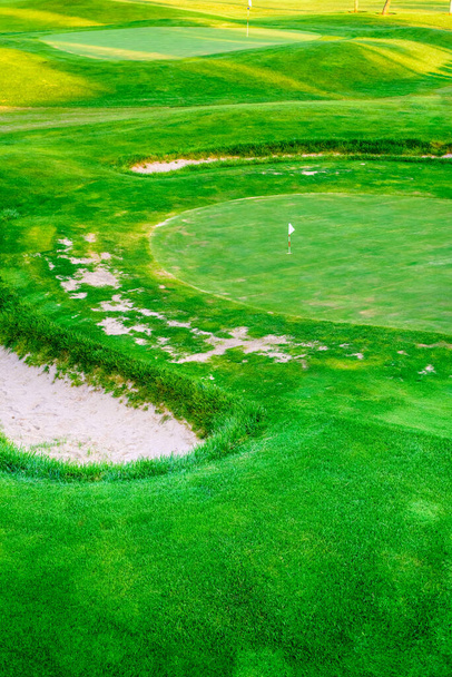 Ένα άδειο γήπεδο γκολφ πράσινο λίγο πιο κάτω. - Φωτογραφία, εικόνα