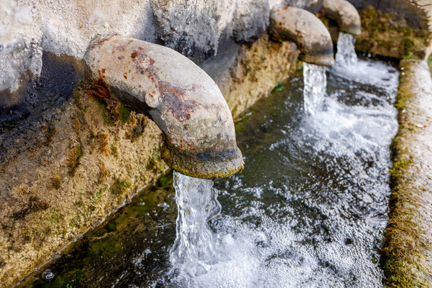 Alte Frischwasserdüsen an einem öffentlichen Brunnen in den Bergen. - Foto, Bild