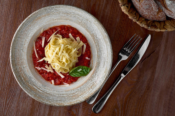 Pasta fettuccine with tomato sauce with the oak Parmesan and basil on a plate, delicious Italian dish. - Fotoğraf, Görsel