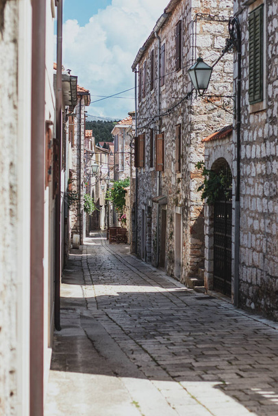 Enge alte Gassen in der Stadt Starigrad auf der Insel Hvar. Steinhäuser im alten griechischen Stil und ein schmaler gepflasterter Fußweg, der durch sie führt - Foto, Bild