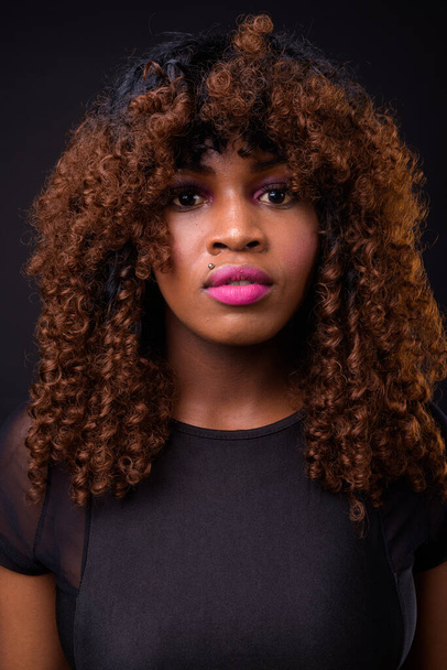 Studio shot van jonge mooie Afrikaanse vrouw tegen zwarte achtergrond - Foto, afbeelding