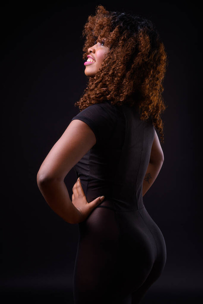 Studio shot of young beautiful African woman against black background - Foto, Imagen